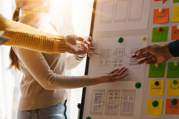 A UX design team is a confluence of user research, UX, UI design with layout paper on desk.