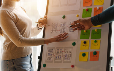 A UX design team is a confluence of user research, UX, UI design with layout paper on desk.