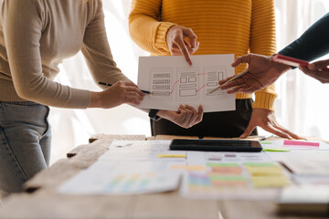 A UX design team is a confluence of user research, UX, UI design with layout paper on desk.