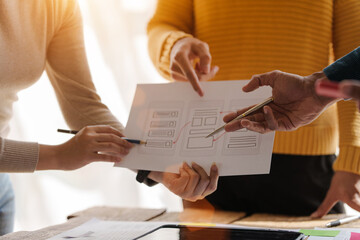 A UX design team is a confluence of user research, UX, UI design with layout paper on desk.
