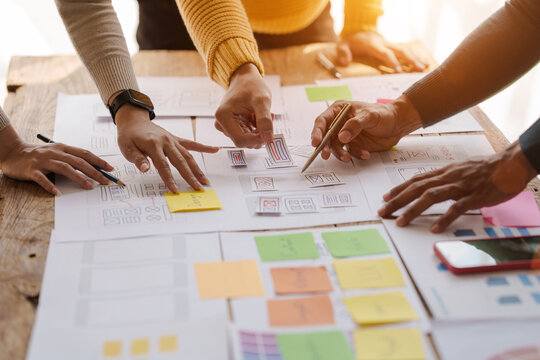 A UX design team is a confluence of user research, UX, UI design with layout paper on desk. - Powered by Adobe