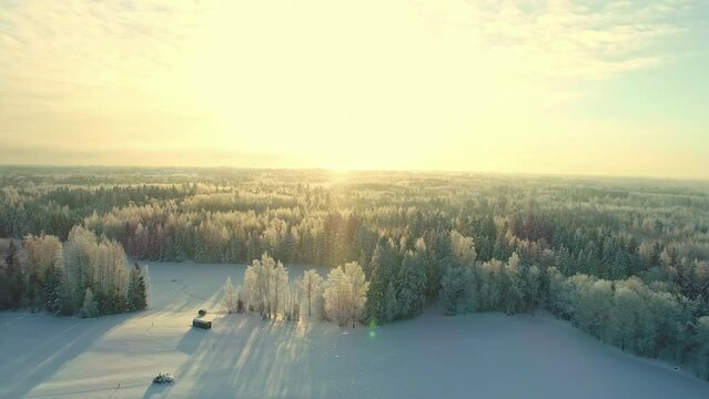 Aerial view of alternative living with saunas in small cabins in a snowy forest landscape. Sunset over a fabulously calm landscape in winter