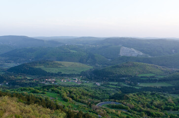 Scenic view to beautiful green hills and big bridge against red orange sky in spring from Črni Kal, Slovenia
