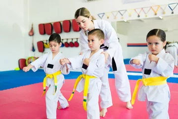 Tuinposter Active kids practicing karate with a martial arts trainer © AntonioDiaz