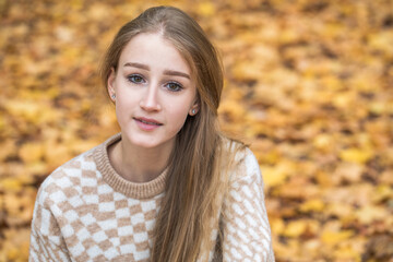 Portrait of a young beautiful blonde girl in an autumn park