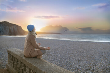 A woman meditates against the backdrop of alabaster rocks and the atlantic ocean