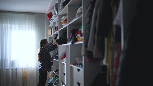 The mother is a housewife looking for clothes in the closet.