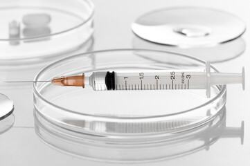 Syringe with liquid transparent vaccine for injection on petri dish in medical laboratory testing white background