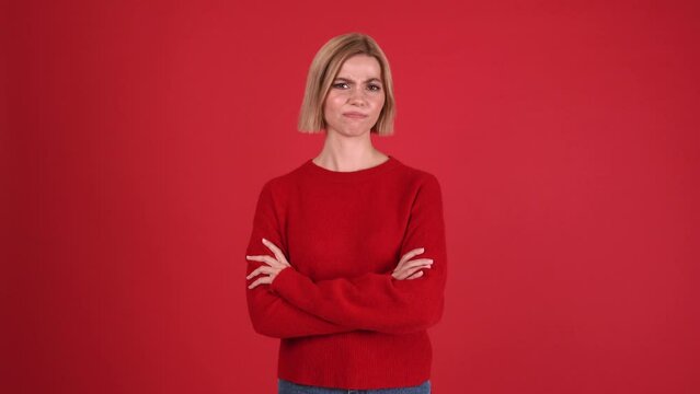 Pensive blonde woman wearing red sweater disagrees with something in the red studio