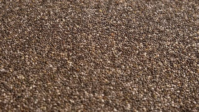 Chia Seeds Wallpaper. Raw Chia Seeds Rotating on Turntable. Close Up, Top View, Macro. Superfood. Spinning. Full Frame. Food Background. Shiny textured White, Gray and Brown Chia. Paleo Diet Concept.