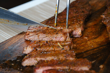 Cutting juicy top blade steak on wooden cutting board