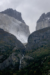 Fototapeta na wymiar Dramatic scene of rocky mountains with small waterfall on a cloudy mist day