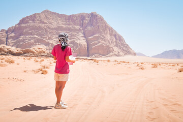 Young caucasian woman hold map disoriented lost read map alone in desert in extreme heat. Wadi rum...