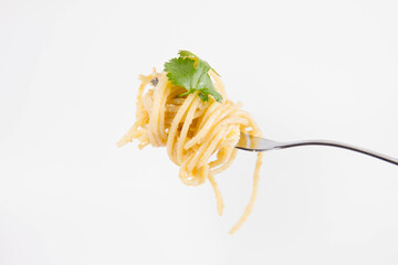 Yellow pepper pesto spaghetti covered with grated mozzarella cheese decorated with coriander rolled around a fork - 542682920