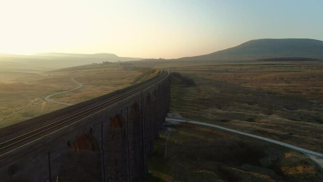 Aerial Drone Shot Close Along Ribblehead Viaduct Train Bridge at Stunning Sunrise in Summer in Yorkshire Dales England UK with 3 Peaks Ingleborough in Background