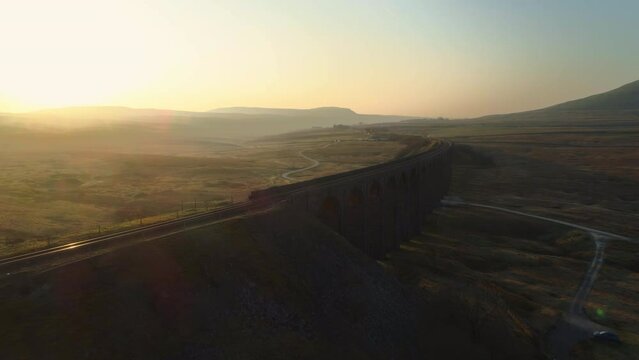 Low Close Aerial Drone Shot Rotating Around Ribblehead Viaduct Train Bridge at Stunning Sunrise in Summer in Yorkshire Dales England UK with 3 Peaks Ingleborough Mountain in Background