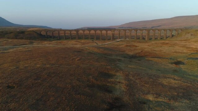 Front On Aerial Drone Shot Flying and Rising Towards and Over Ribblehead Viaduct Train Bridge at Stunning Sunrise in Summer in Yorkshire Dales England UK