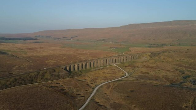 Aerial Drone Shot Rotating showing Ribblehead Viaduct Train Bridge from far away at Stunning Sunrise in Summer in Yorkshire Dales England UK with 3 Peaks Whernside Mountain in background