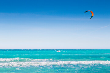 Kite surfing, man surfing in blue sea under clear sky
