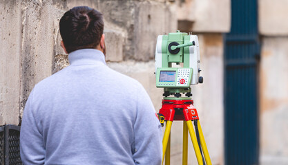 Un géomètre et topographe mesurant une distance dans la rue.