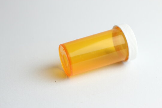 An Empty Orange Pill Bottle Is Placed On A White Background.