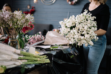 Young female florist woman working, holding in her hands big fresh bunch of aromatic matthiola flowers