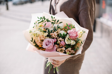 Very nice young woman holding big and beautiful flower bouquet of fresh roses, eustoma, pistachio, matthiola in pink and pastel cream colors, close up view - 542687706