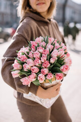 Very nice young woman holding beautiful floral mono composition of fresh pink tulip flowers,...