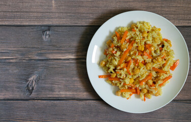 Pilaf with rice, chickpeas and spices on wooden background with copy space