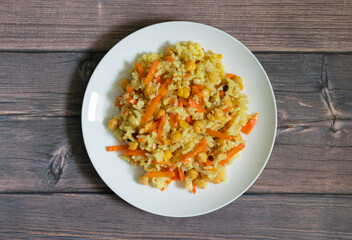 Pilaf with Basmati rice, chickpeas and spices on a wooden background centered