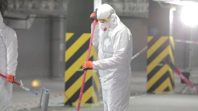 The process of applying polymer material to the floor. Builder in a white protective suit. A builder in a clean protective suit does the work. Construction worker at modern construction site