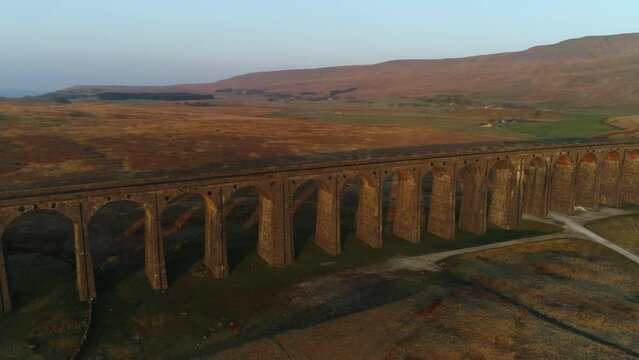 Aerial Drone Shot Rotating Around Ribblehead Viaduct Train Bridge at Stunning Sunrise in Summer in Yorkshire Dales England UK with 3 Peaks Whernside Mountain in Background