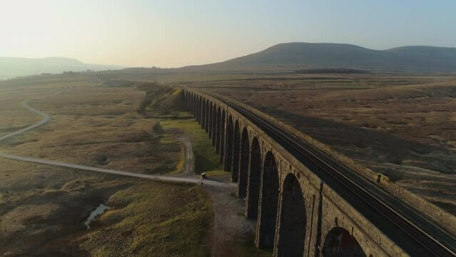 Low Aerial Drone Shot Closeup to Ribblehead Viaduct Train Bridge at Stunning Sunrise in Summer in Yorkshire Dales England UK with 3 Peaks Ingleborough Mountain in Background
