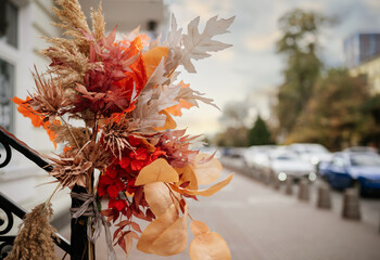 A bouquet of yellow leaves decorates the entrance to shops on the street of the autumn city.