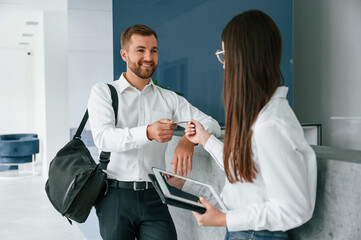 Obraz premium Man in white shirt is ordering a room in the hotel by woman's help