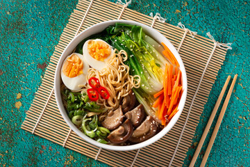 Ramen noodle soup with eggs, mushrooms, pak choi in white bowl