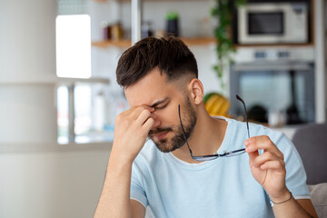 Tired man taking off glasses rubbing dry irritated eyes to relieve pain feeling discomfort suffers...
