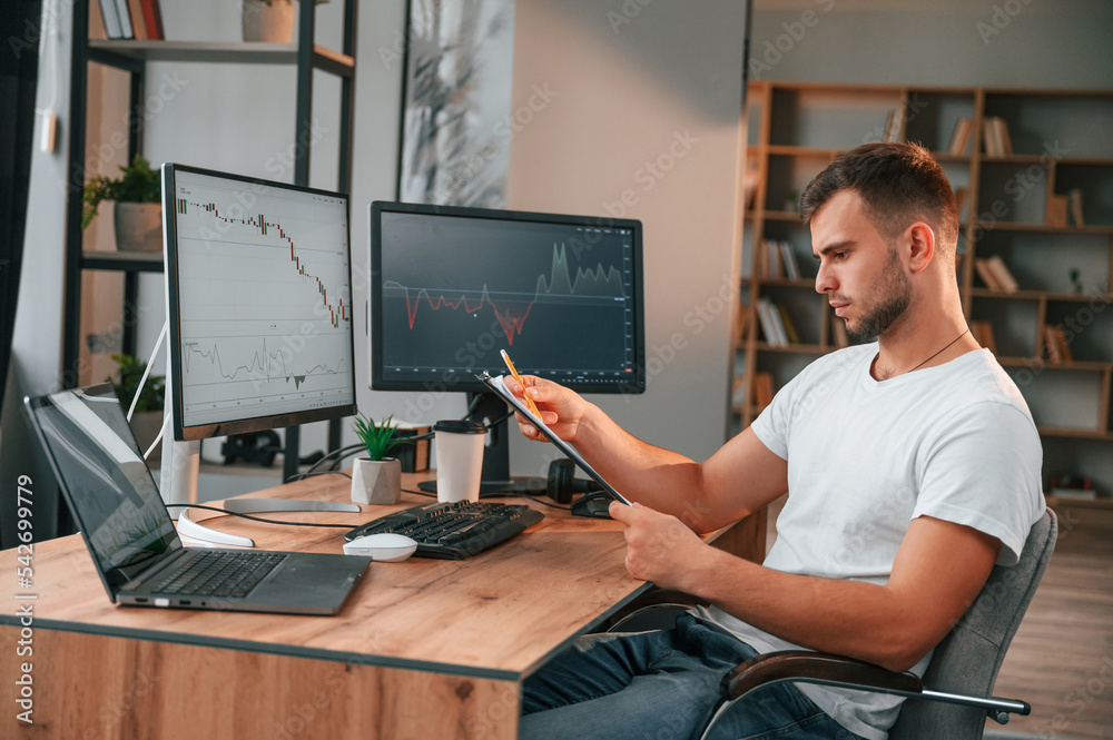 Fototapete Laptop is on the table. Young stock broker is working in the office by using computer