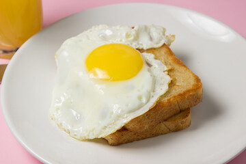 Fried eggs on a pink background. Breakfast of Fried eggs on fried bread and a glass of juice