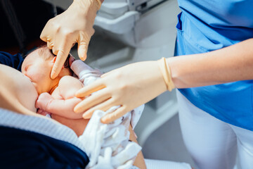 Breast feeding, a new born sucking mother breast. Female breastfeeding consultant in medical gloves...