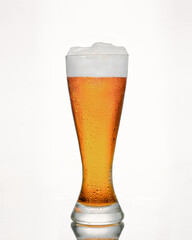 A glass of cold beer with foam, bubbles in a drink, on a white background, isolated