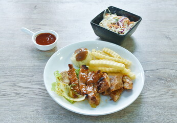 grilled pork steak dressing barbecue sauce with mashed potato and salad dipping chili sauce on plate 