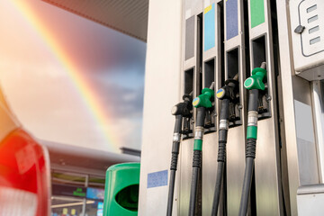 Colorful petrol and diesel nozzles of the dispenser machine at the gas fuel station against rainbow...