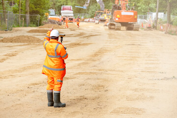 Surveyor site engineers working with electronic theodolite and GPS on road construction site