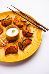 Tandoori momo, veg or non veg in red and cream sauce, served with sauce.  Nepal and Tibet recipe