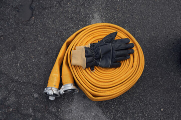 Top view of yellow fire hose with black gloves on it on the ground - Powered by Adobe