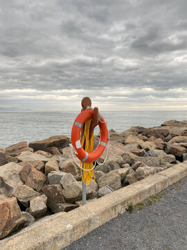 Bou&eacute;e de sauvetage orange sur le bord d'une jet&eacute;e. Anneau de s&eacute;curit&eacute; pour des sauvetage en mer. Bou&eacute;e de s&eacute;curit&eacute; sur un quai. Paysage nuageux d'une plage. Concept de noyade et de vie en danger.