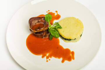 delicious beef tongue with green, potato gratin and sweet sour sause on a white plate and white background