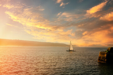 Fototapeta na wymiar sailing boat sailing on the waves of the north sea in scarborough at sunset