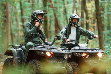 Wearing helmets. Two male atv riders is in the forest together © standret